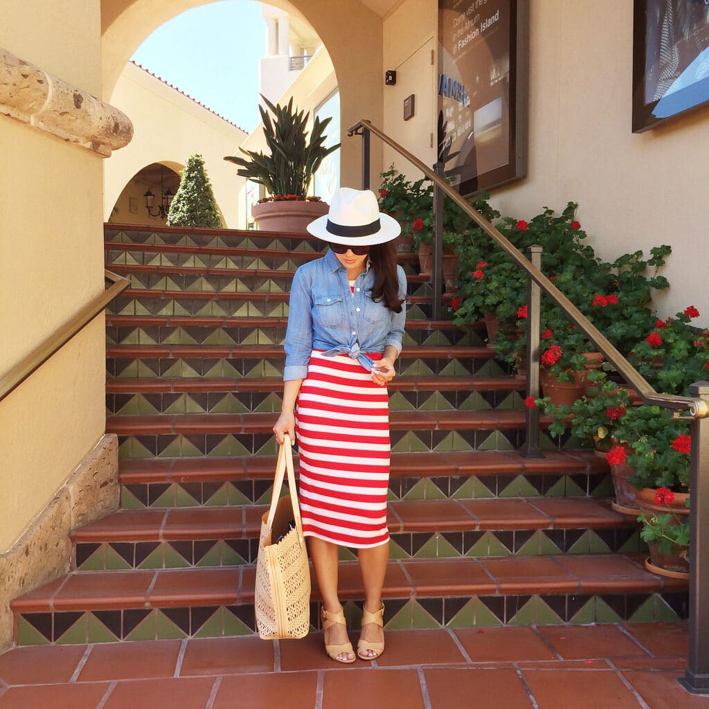 Annie Mai Thai wearing a red and white striped skirt, blue shirt, and white hat. 