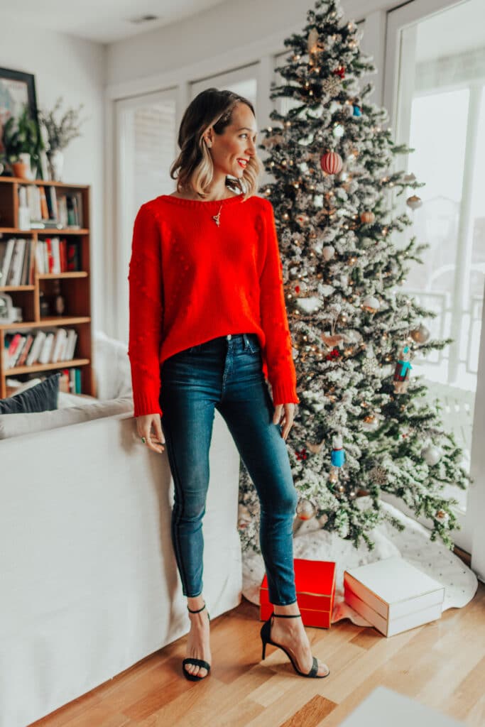 blair staky's festive outfit featuring strappy heels, dark blue skinny jeans, and red sweater