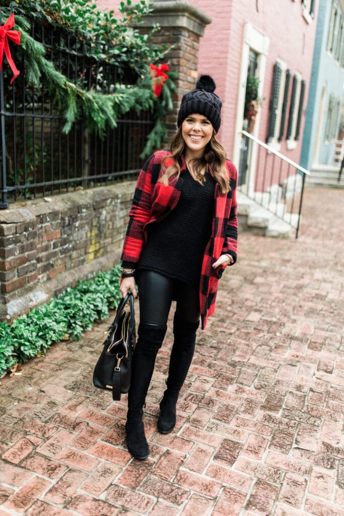 Shelby Back's outfit with a red buffalo plaid coat, black beanie, black leather leggings, over the knee boots, and black sweater.