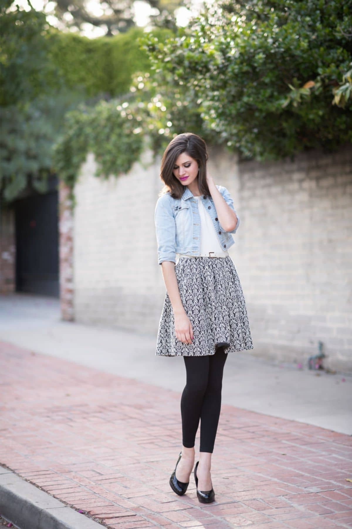 outfit with black leggings, black heels, light denim jacket, and black and white print skirt
