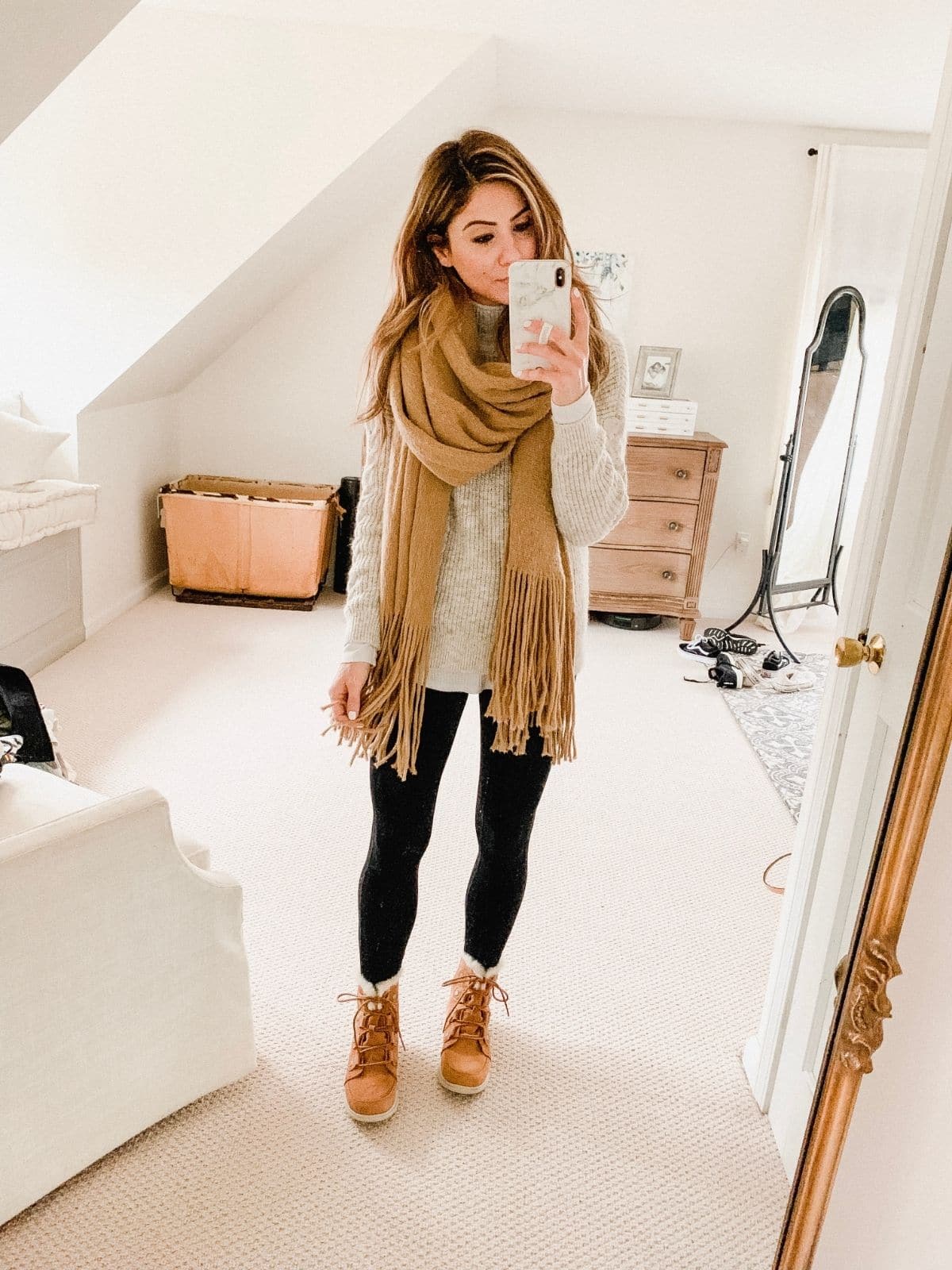 outfit with brown boots, black leggings, cream top, and brown scarf