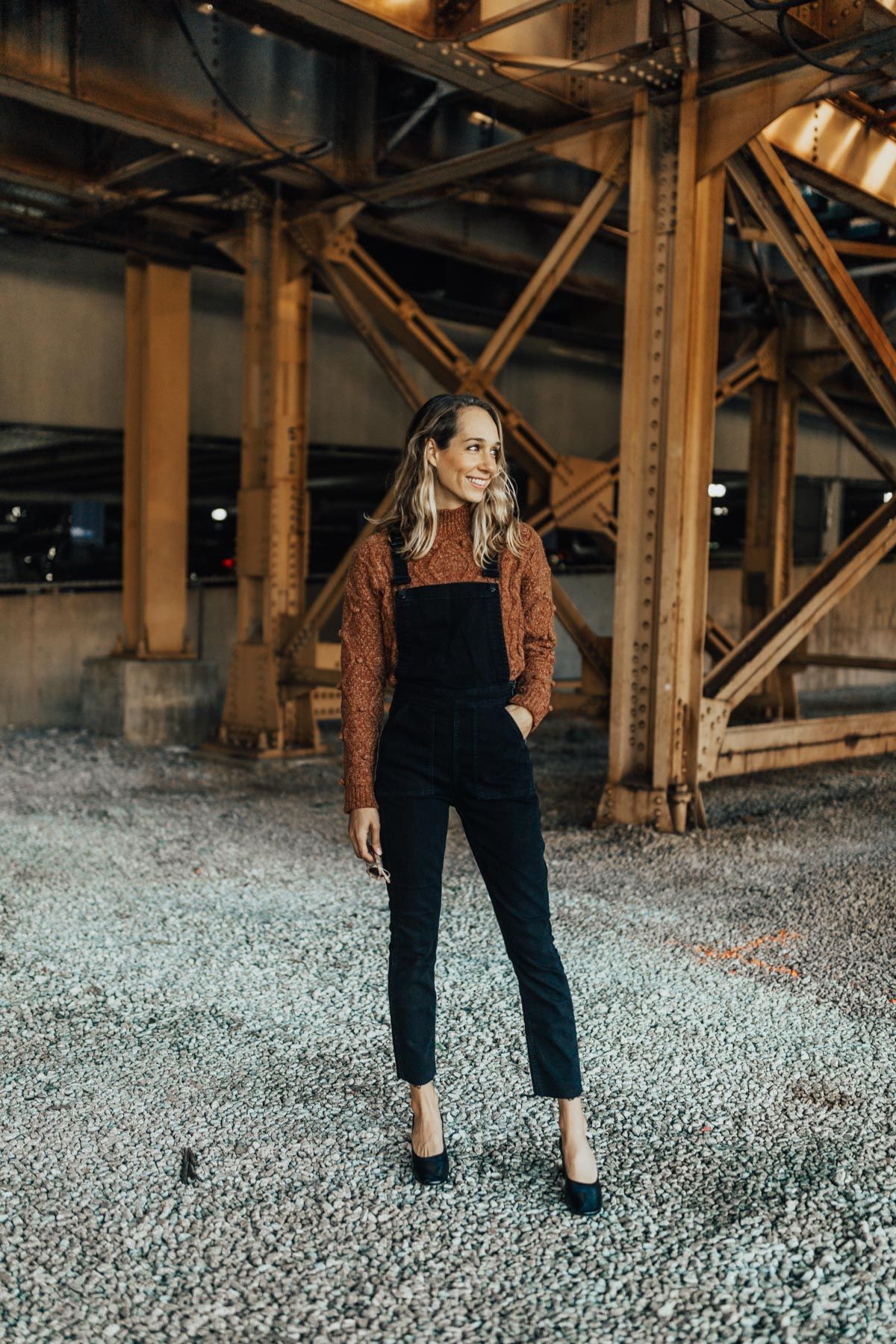 styling black overalls with brown sweater