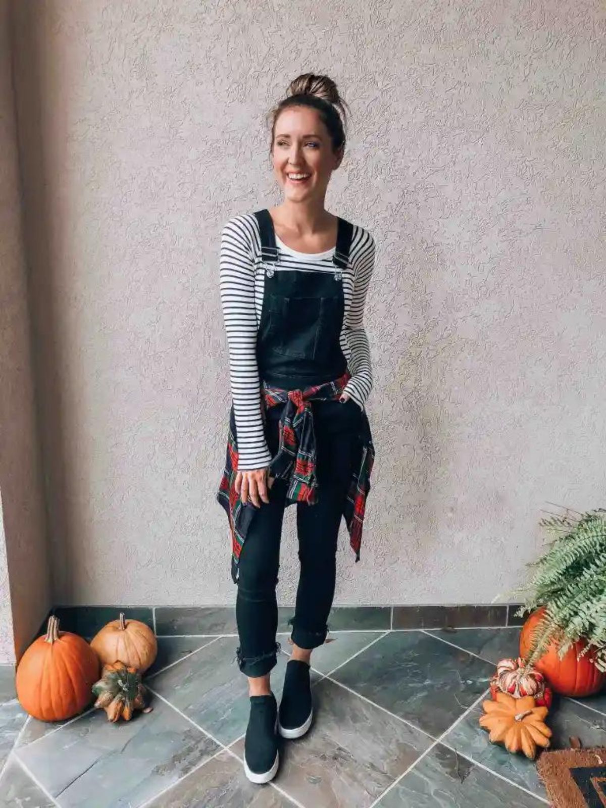 styling black slim overalls with long sleeve shirt and flannel tied around the waist