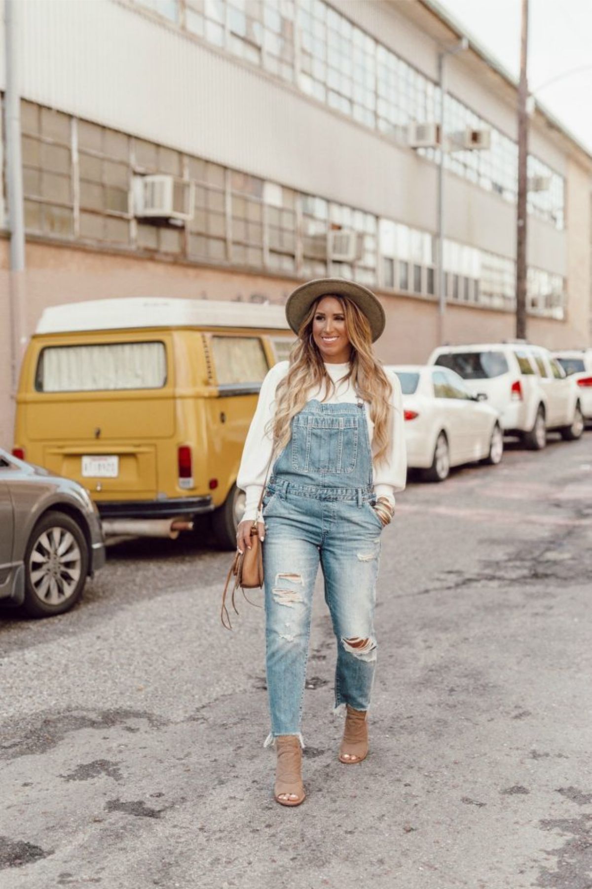 styling light overalls with hat and loose sweater