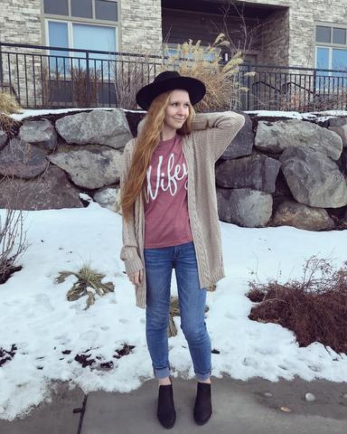 fall outfit featuring pink wifey shirt, black hat, blue skinny jeans and black booties