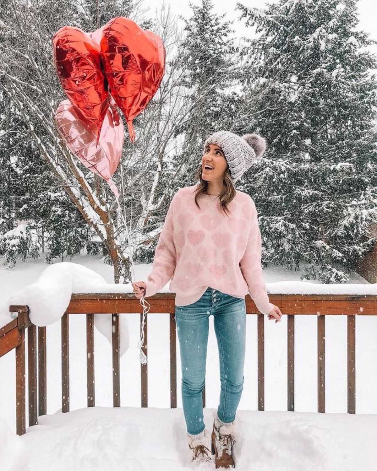 outfit with pink heart sweatshirt, beanie, blue jeans, and boots