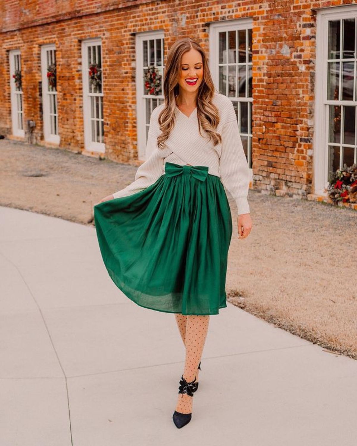 holiday outfit with loose white top, green skirt with a bow, and heels