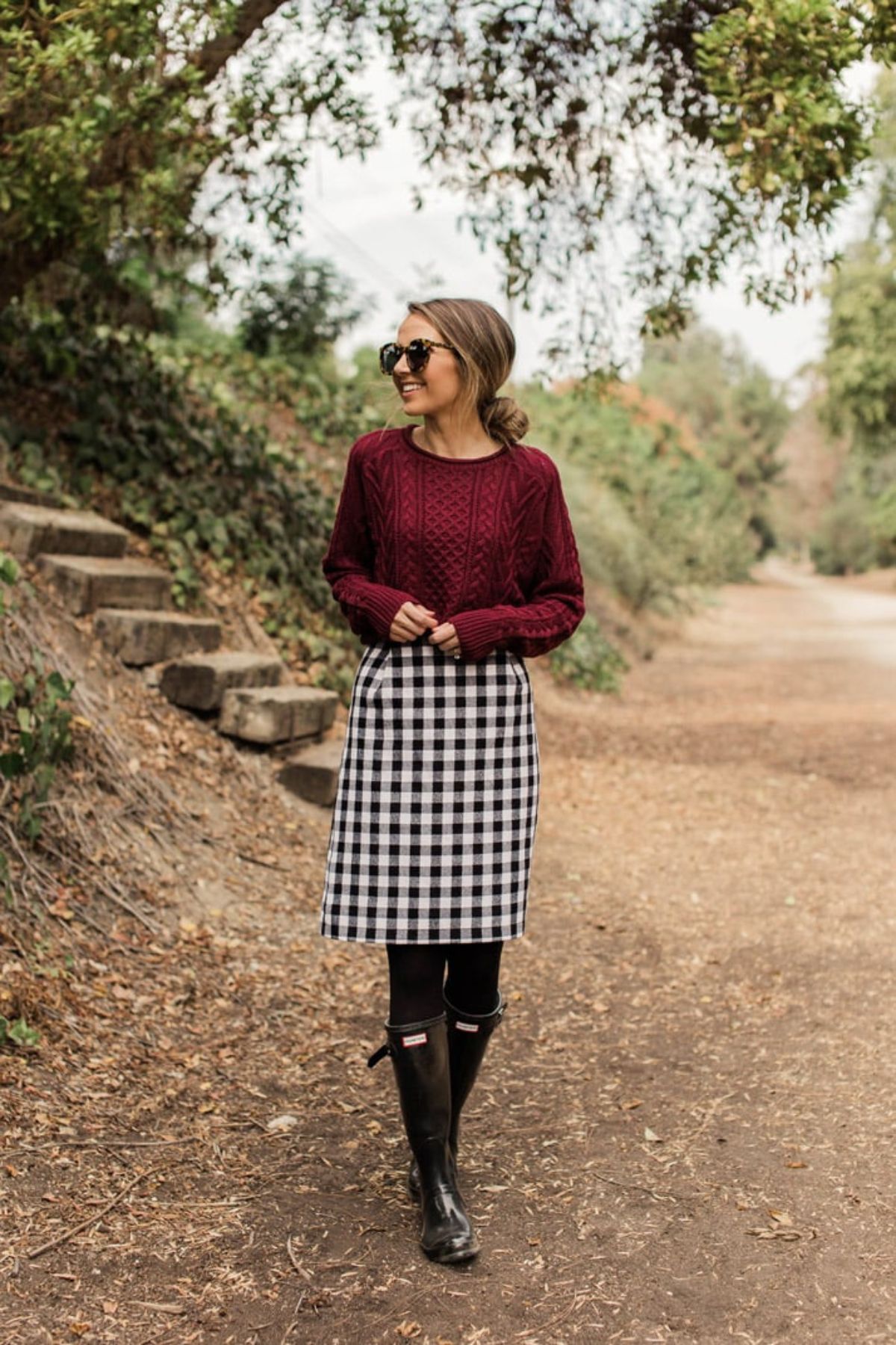 holiday outfit with burgundy sweater, buffalo plaid skirt, and black hunter boots