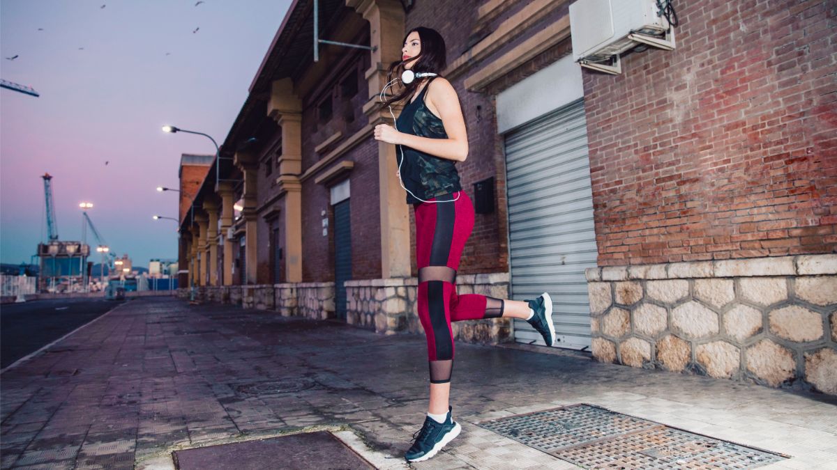 beautiful and physically fit brunette running on sidewalk