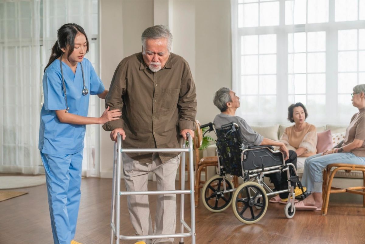 nurse helping elderly man walk with walker