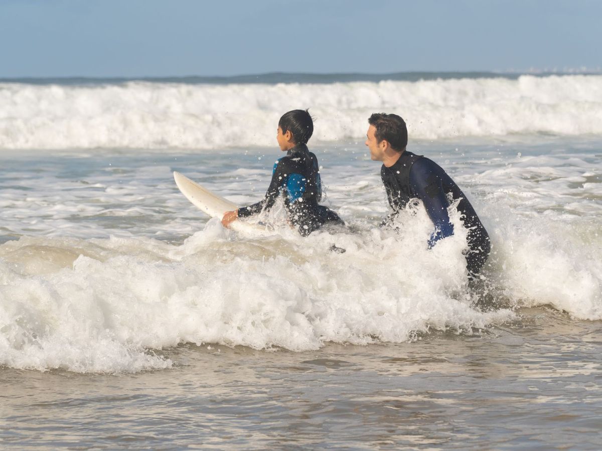 man guiding a boy in surfing