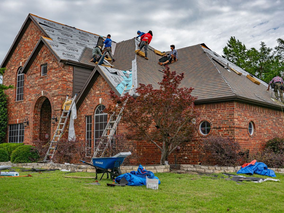 workers renovating roof of brick house in texas